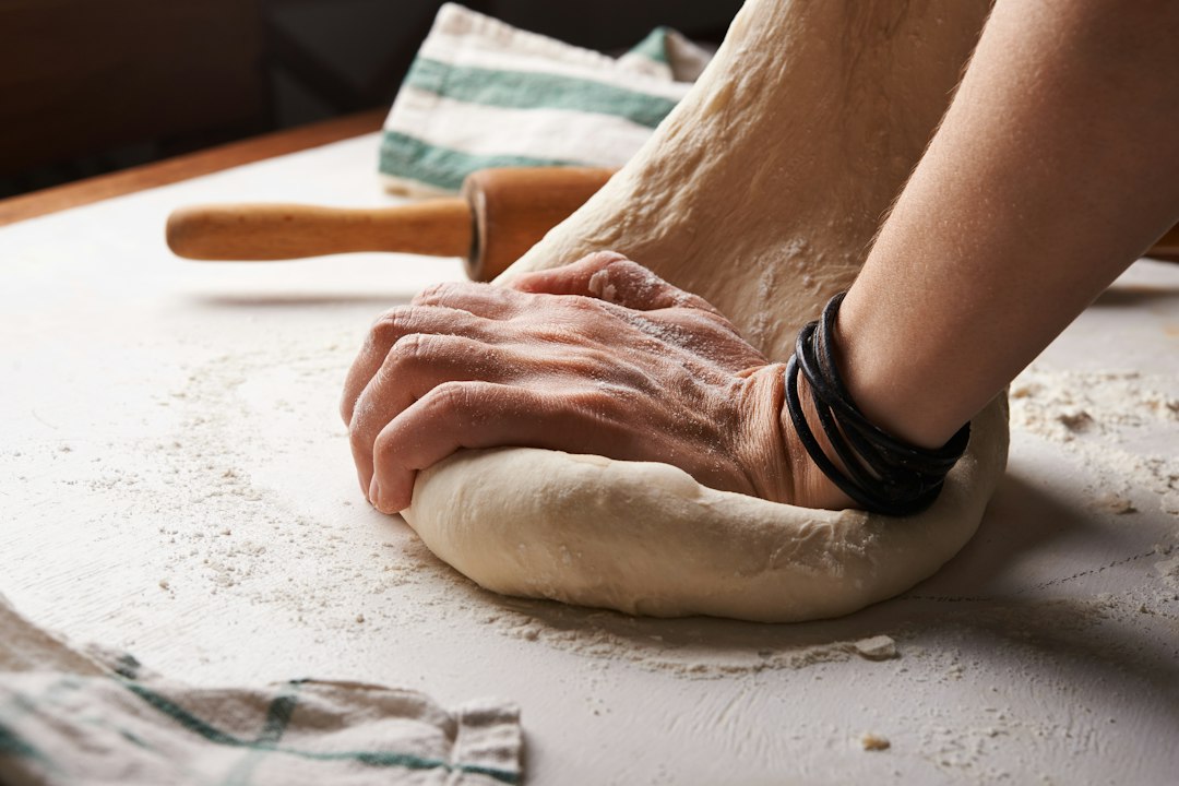 Hands preparing pizza dough on a floured work surface
